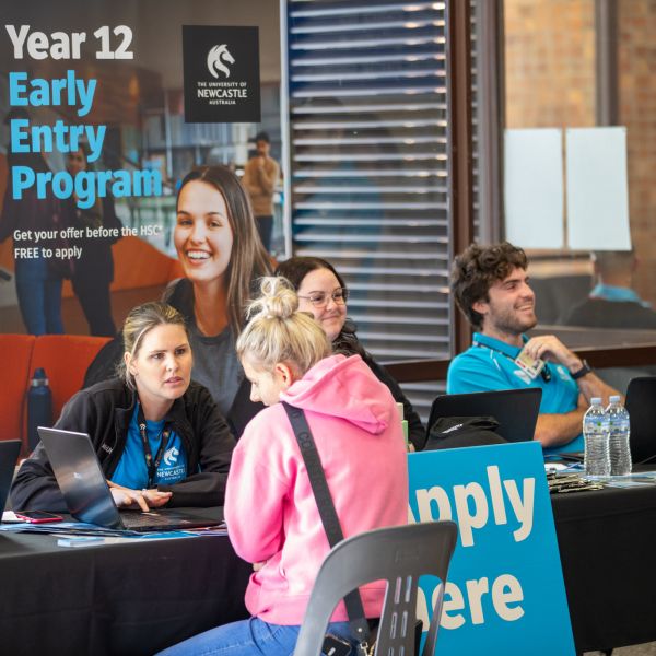 A person talks to a staff member at an information desk for Early Entry. Students receive Early Entry offers and extra support ahead of HSC exams
