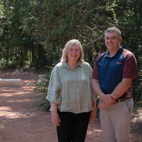 Man and woman posing for a picture in front of bushland