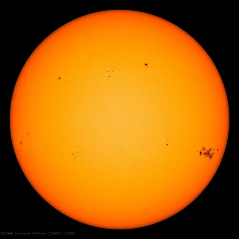 Close up photo of the sun in shades of orange showing a large dark spot on the right side