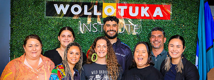 A group of people all smiling in front of a green wall