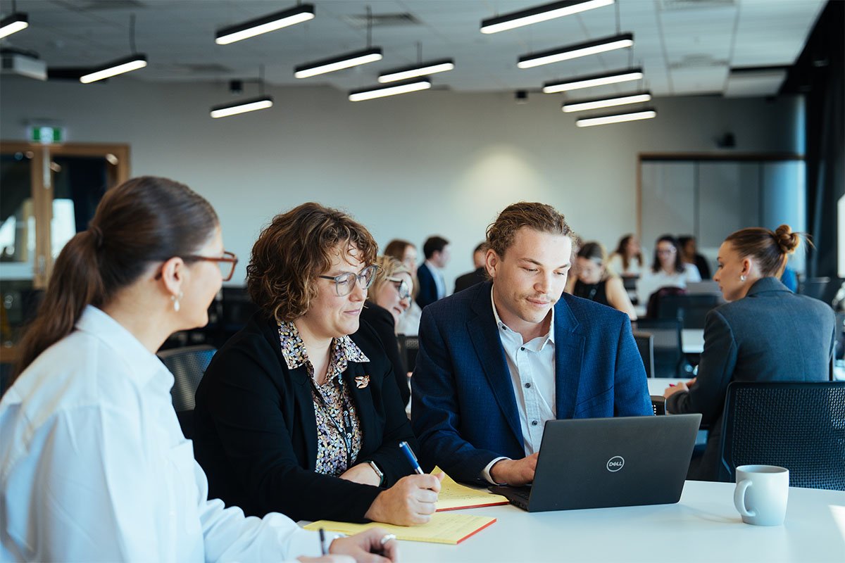 Three people in suits at a desk