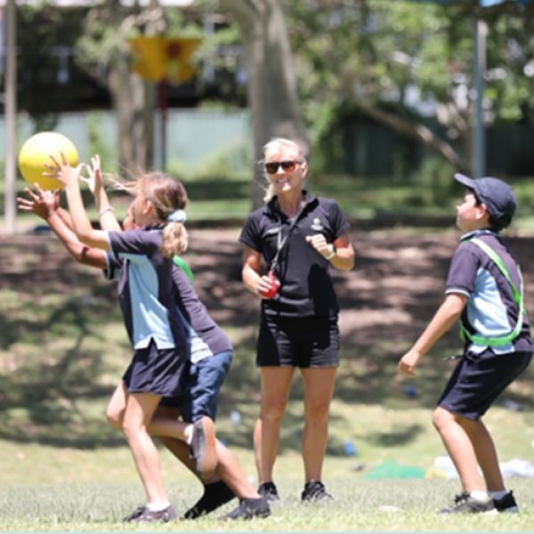 Associate Professor Narelle Eather adjudicates three school children playing team sport as part of the Education, Movement, & Understanding (EMU) program