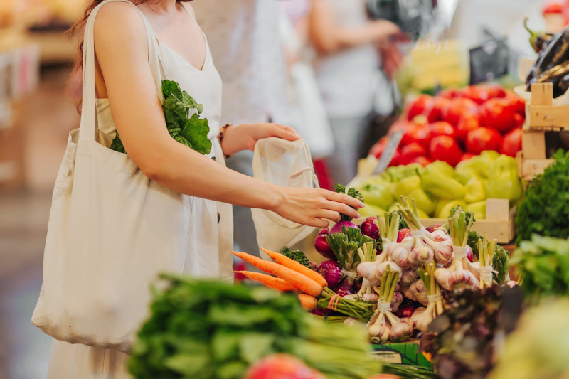 Stock imagery shows a woman picking out fresh vegetable produce