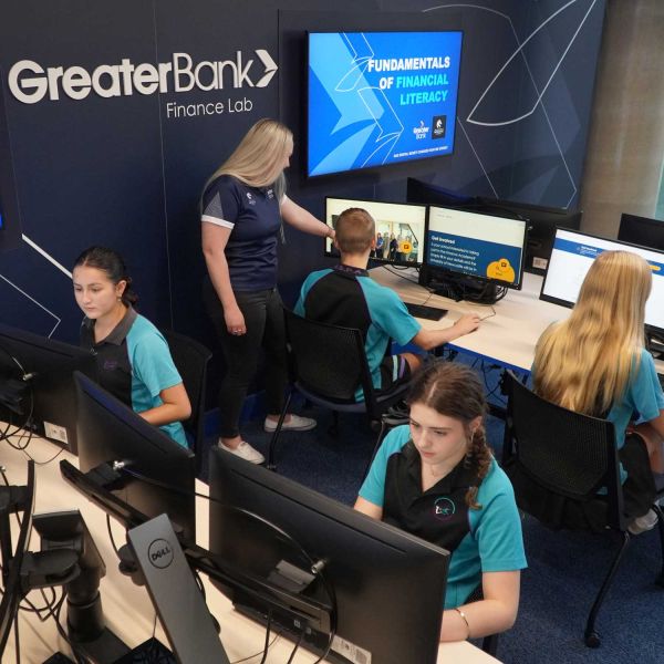 Four high school students sitting at computer desks in the Greater Bank Finance Lab, learning about financial skills.. Banking on Brighter Futures.