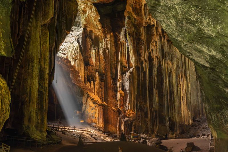 View inside a cave, showing illuminated stalactite formations and a walking path.