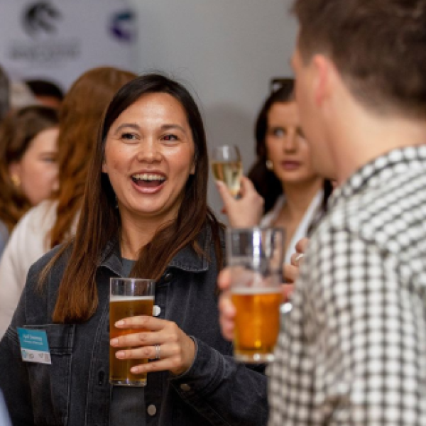 Young alumni smiling and networking while holding drinks