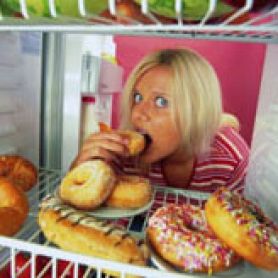 Girl with head in fridge eating donuts. Researchers delve into world of food addiction