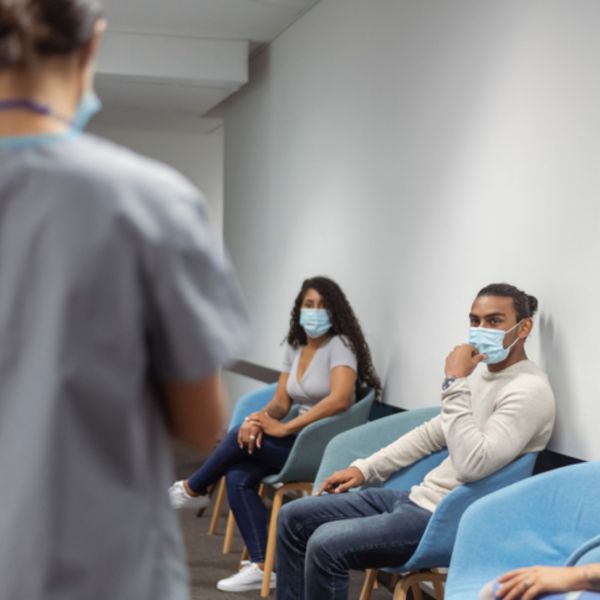 male and female sitting in a hospital waiting room wearing face masks