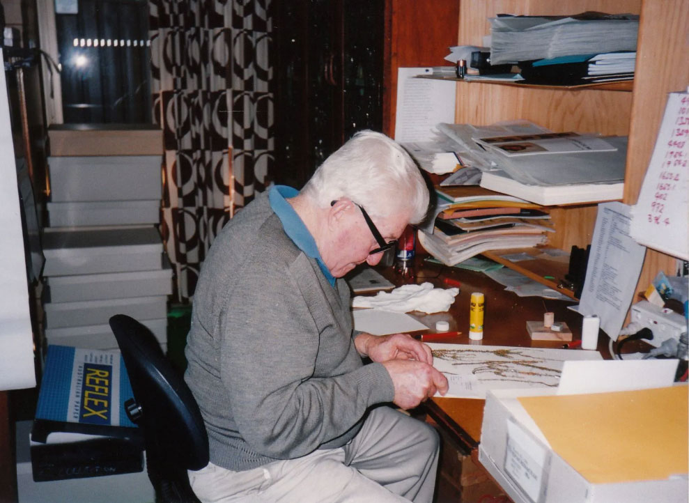 Don McNair sits at a desk, looking at specimens