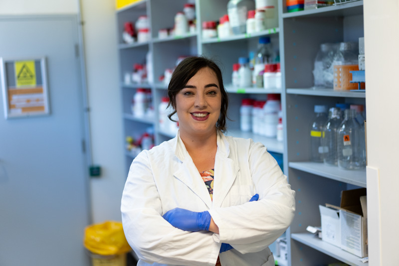 Dr Martin in a lab setting, smiling to camera