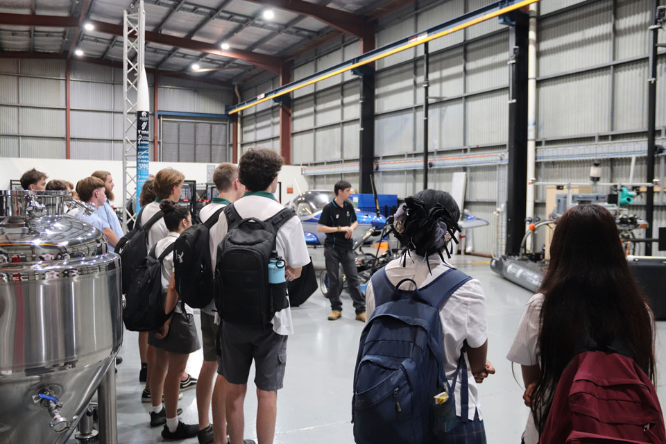 Students stand in a building surrounded by engineered vehicles and equipment