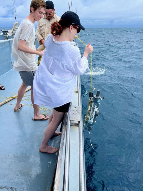 Students stand on a boat, pulling equipment out of the ocean