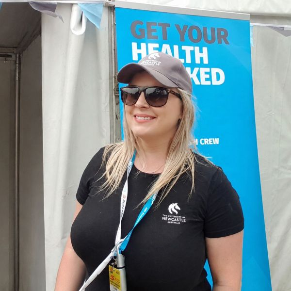 Image of Caitlin with sunglasses, smiling at the camera while volunteering at a uni event