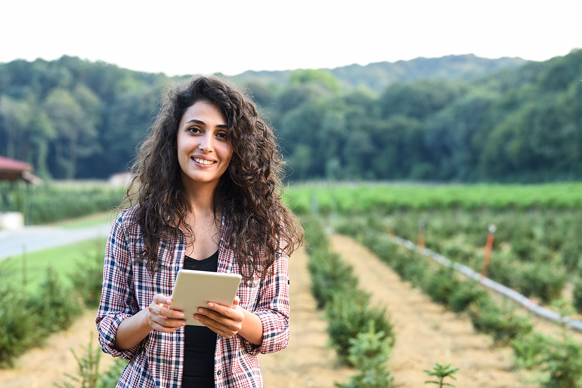 environmental science postgraduate student in greenhouse with computer.
