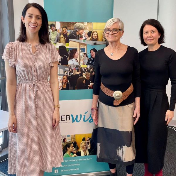 L-R Alix Lasance, Kate Ramsay (event host) and Leah Kiem stand  in front of a HunterWiSE banner. They are facing the camera and smiling.. The Great Divide: Understanding and Addressing the Gender Pay Gap