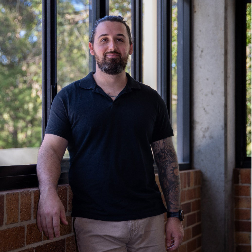 A man standing inside a university building in front of windows