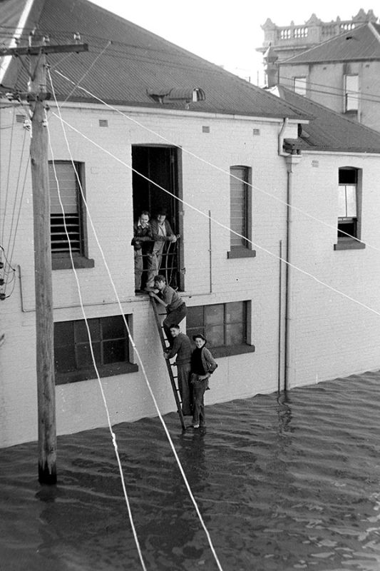 A vertical shot of a deeply flooded Victoria Street in Maitland, NSW, with water reaching high up the buildings, 1955.