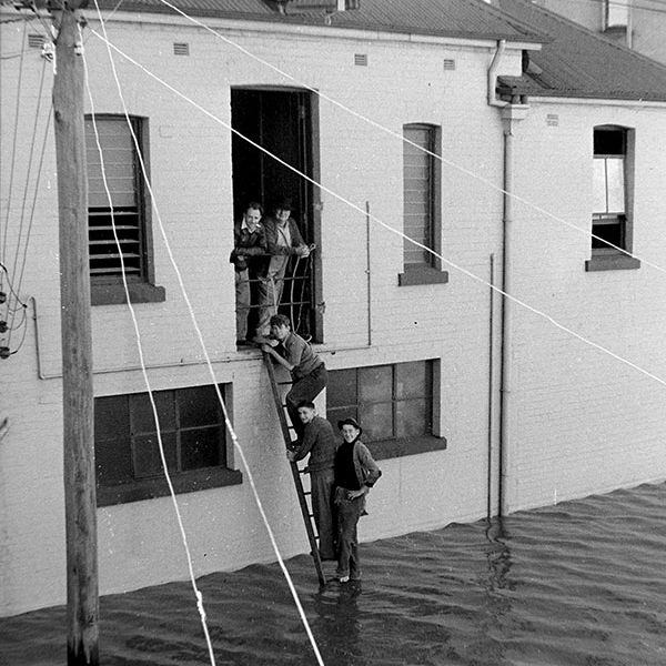 A vertical shot of a deeply flooded Victoria Street in Maitland, NSW, with water reaching high up the buildings, 1955.