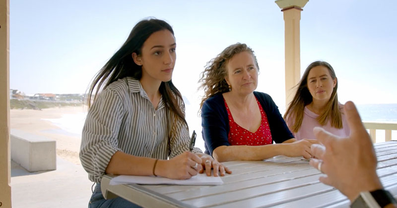 Three women at a table at the beach