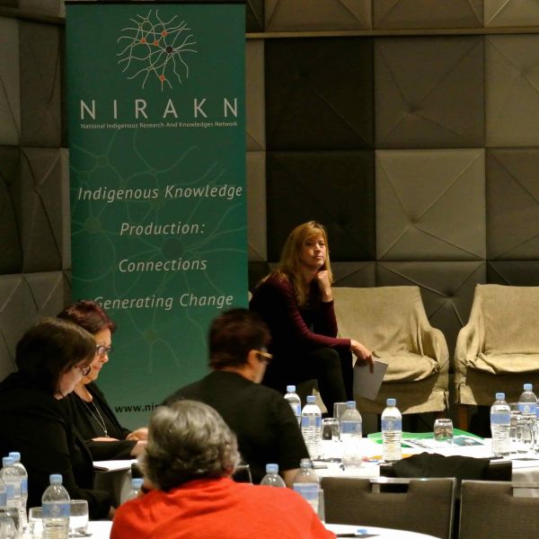a womn on stage looking contemplative and three workshop participants listening and taking notes. Unlocking the chains of oppression: education is key 
