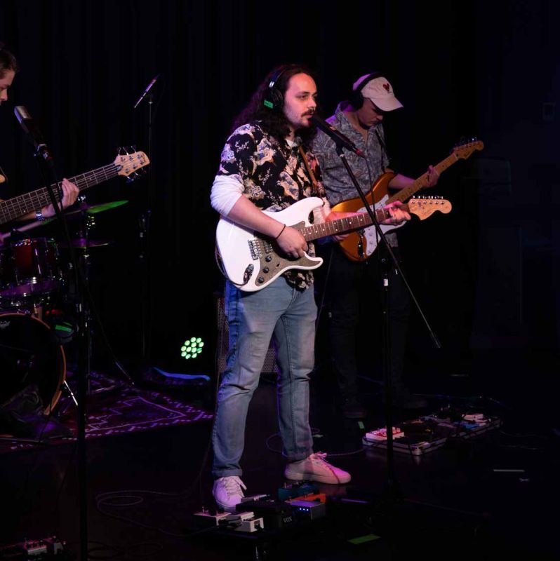 Three guitarists performing on a stage
