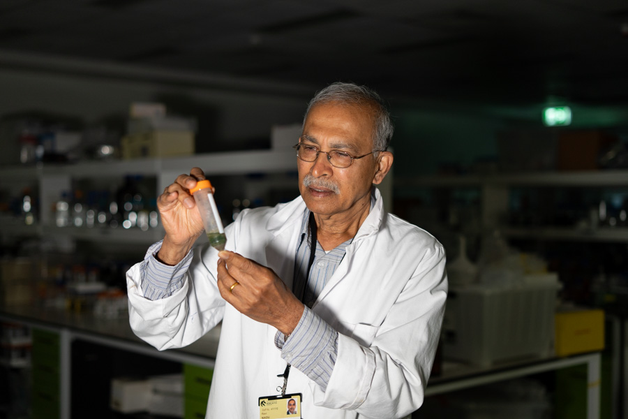 Prof Ravi Naidu Ravi is pictured in a lab, examining a test tube with liquid in it