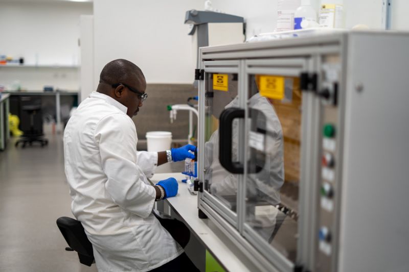 Scientist Simon sits at a lab bench, examining a test tube of liquid