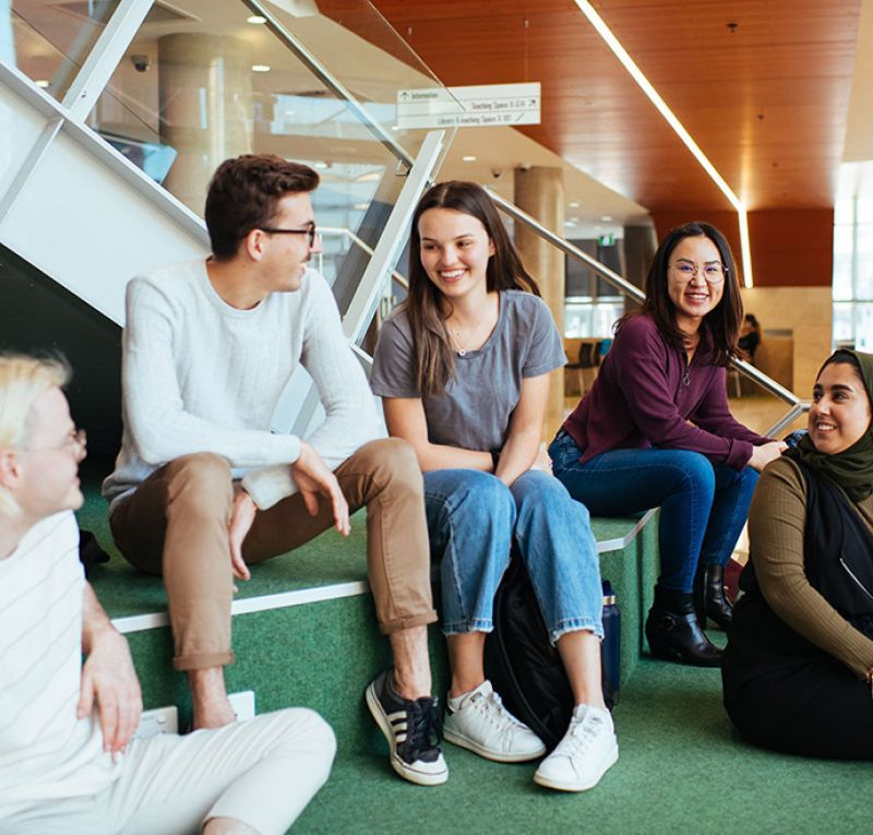 The photograph of a group of students sitting on the stair at NUSpace, having a casual chatl 