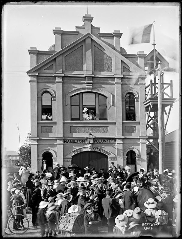 A formal gathering of people outside the newly opened Hamilton Volunteer Fire Station on James Street, Hamilton, NSW, in 1906, with the station's watch tower and bell visible.