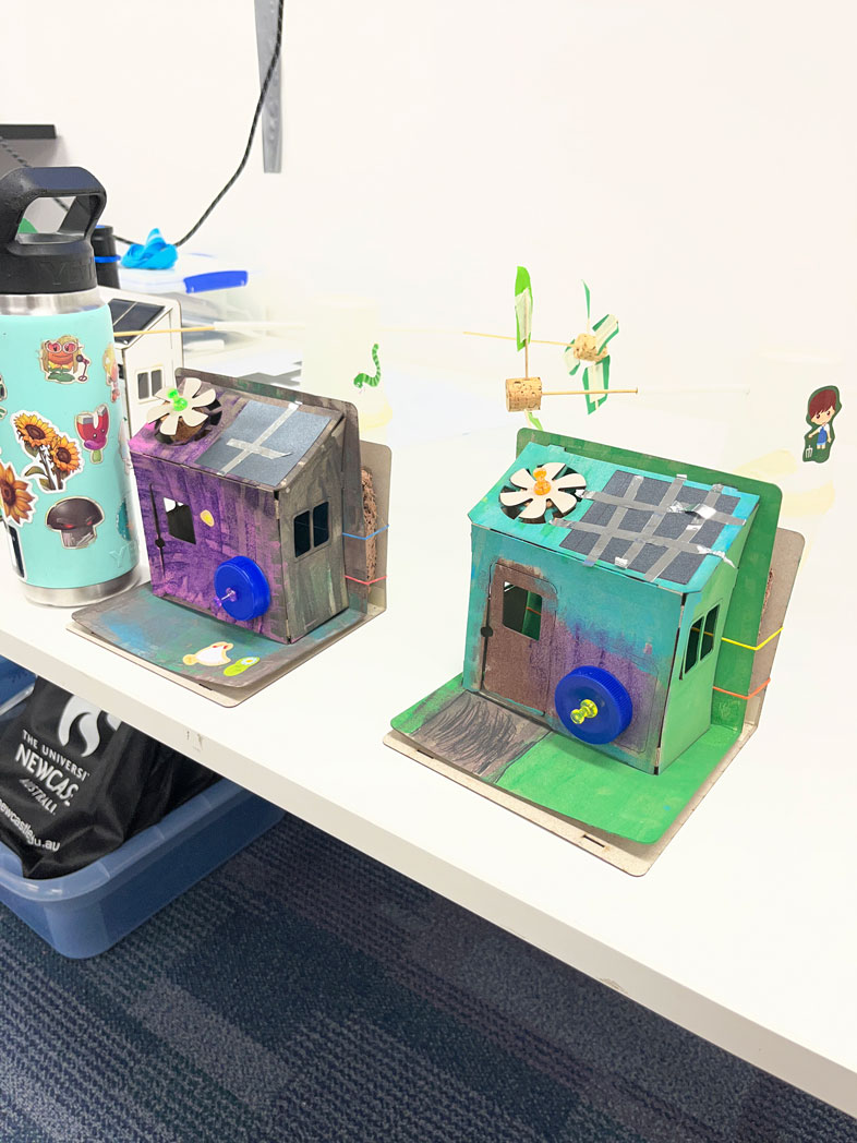 Two brightly-coloured, decorated, eco-houses sit on a table