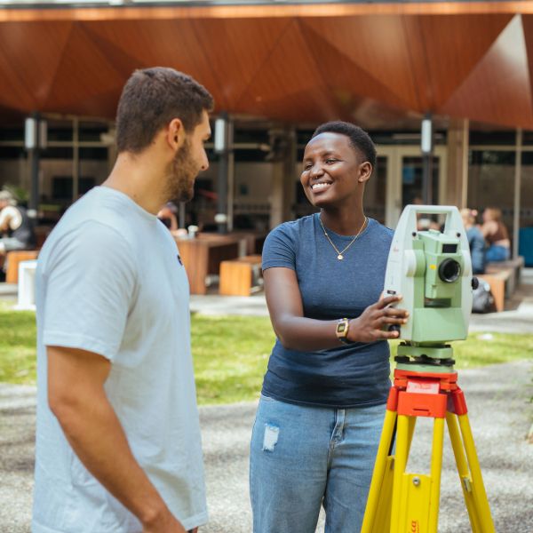 Two surveying students with surveying equipment on the University of Newcastle campus.