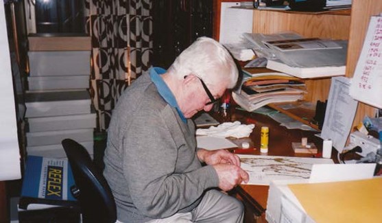 Don McNair sits at a desk, looking at specimens