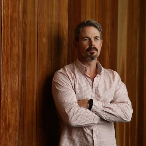 Nathan-Bartlett-thumb.jpg Nathan Barlett standing with his arms folded in front of a wooden wall
